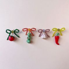 four different types of brooches on a white surface, one with a bell pepper and the other with an eggplant