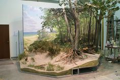 a large painting of trees and sand in a room with other items on the floor