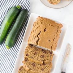 two slices of zucchini bread on a plate next to a cucumber