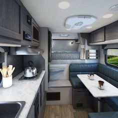 the interior of a recreational vehicle with kitchen and dinning area, including a table