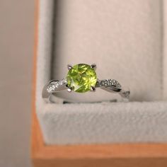 a ring in a box with a green stone and white diamonds on the band,