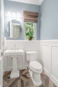 a white toilet sitting next to a sink in a bathroom