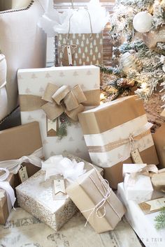 many wrapped presents are stacked next to a christmas tree