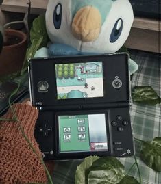 a stuffed animal sitting on top of a nintendo wii game console next to a plush toy