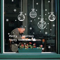 a man is looking out the window at christmas decorations