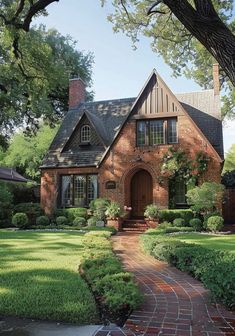 a brick house surrounded by lush green trees and shrubs with a walkway leading to the front door