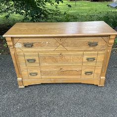 an old wooden dresser sitting in the middle of a driveway with grass and trees behind it