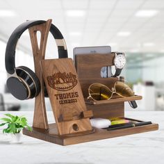 a wooden stand with headphones, sunglasses and other items on it next to a plant