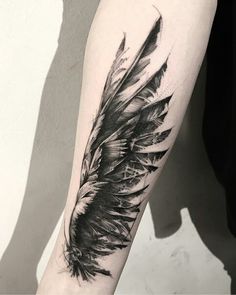 a black and white feather tattoo on the arm