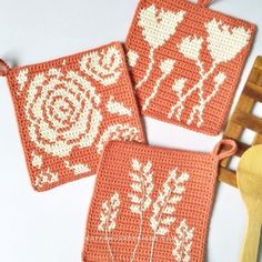 two crocheted coasters with flowers on them next to a wooden spoon and fork