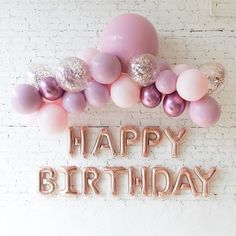 a happy birthday sign with balloons and confetti on the wall in front of it