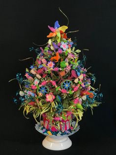 a vase filled with lots of colorful flowers on top of a white table next to a black wall