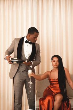 a man in a tuxedo pouring champagne into a woman's dress sitting on a couch