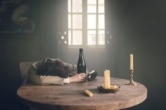 a cat laying on top of a wooden table next to a wine bottle and candle