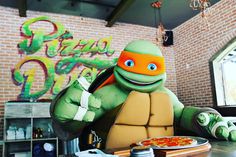 an inflatable turtle sitting at a table eating pizza