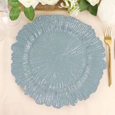 a blue plate sitting on top of a table next to silverware and white flowers