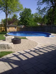 an empty backyard with a large swimming pool and fire pit in the middle of it