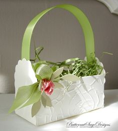 a white bag with green ribbon and flowers in it