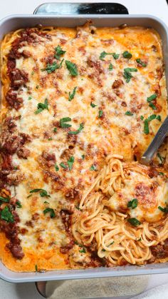 a casserole dish with spaghetti and meat in it, topped with parsley