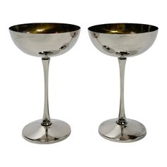 two silver goblets sitting next to each other on a white background, one is empty