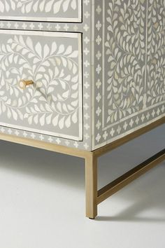 an ornate white and gold chest of drawers with two doors on each side, one door open to reveal the drawer