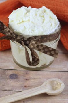 a jar filled with whipped cream on top of a wooden table next to an orange towel