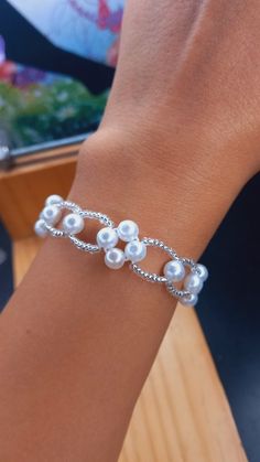 a woman wearing a bracelet with pearls on it