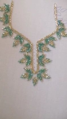 a green and gold necklace on a mannequin's neckline with leaves