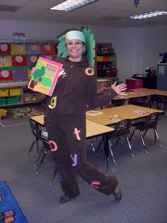 a person in a costume holding up some books and posing for the camera while standing in front of desks