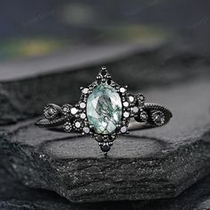 a ring with a green stone surrounded by diamonds