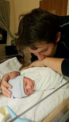 a woman holding a baby in her arms while looking at it's head and arm