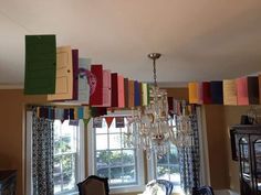 a chandelier hanging from the ceiling in front of a window with colorful paper streamers