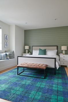 a bed room with a neatly made bed and a blue area rug on the floor