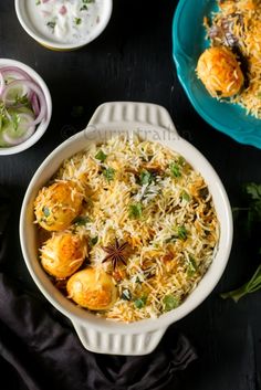 two bowls filled with rice and vegetables on top of a black table next to other dishes