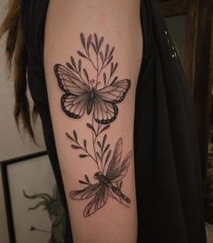 a woman's arm with black and white tattoos on it, including two butterflies