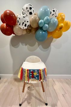 a baby highchair in front of a wall with balloons attached to the back