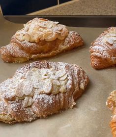 four croissants covered in powdered sugar on top of a baking sheet