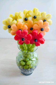 a glass vase filled with fruit and flowers