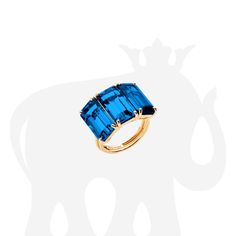 JR0081-LBT-Y 'Gossip' Three Stone Emerald Cut London Blue Topaz Ring in 18K Yellow Gold. Stone size: 13 x 7 mm Approx. gemstone Wt: 14.07 Carats (London Blue Topaz) Luxury Blue Topaz Ring With Polished Finish, Luxury Polished Blue Topaz Ring, Luxury Blue Topaz Ring With Vs Clarity, Ring Settings, London Blue Topaz Ring, Gold Stone, Precious Gems, London Blue Topaz, Blue Topaz Ring