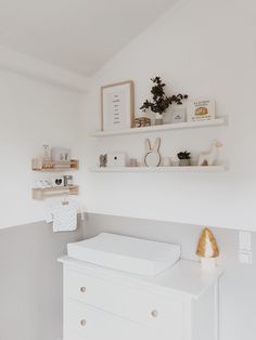 a baby's room with white walls and shelves on the wall, including a crib