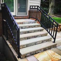 a set of stone steps leading up to a house with black railings and handrails