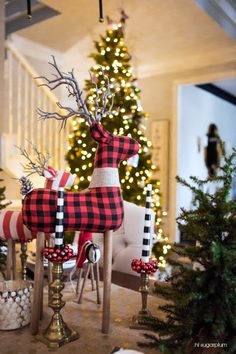 the christmas tree is decorated with red, black and white plaid reindeer decorations in front of it