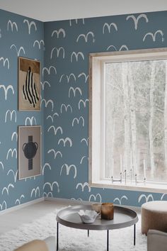 a living room with blue and white wallpaper, two chairs and a coffee table