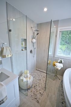 a bathroom with a walk in shower next to a white sink and bathtub under a window