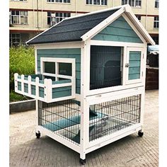 a small blue and white dog house with a black roof on the sidewalk in front of a building