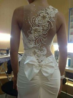 the back of a woman's wedding dress with pearls on it, in front of a computer screen