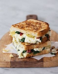 two grilled sandwiches stacked on top of each other with cheese and spinach in the middle