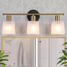 a bathroom vanity with three lights and a mirror in front of the light fixture on the wall