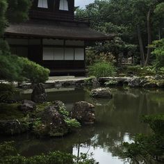 a small pond in front of a building surrounded by trees