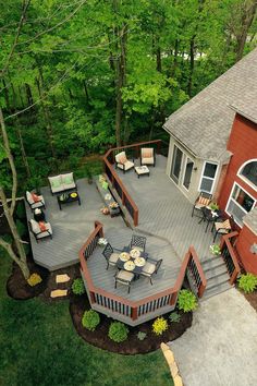 an aerial view of a deck and patio with seating area in the foreground, surrounded by trees